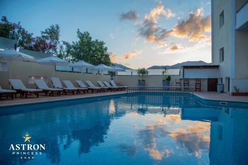 a swimming pool with chairs and a sunset at Hotel Astron Princess in Karpathos