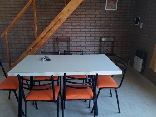 a white table and chairs in a room with a brick wall at Complejo M&M in Bialet Massé