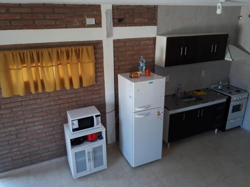a small kitchen with a white refrigerator and a microwave at Complejo M&M in Bialet Massé