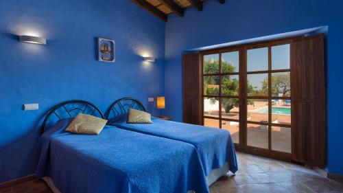 a blue bedroom with two beds and a window at Casinhas Wheelchair friendly in Boliqueime