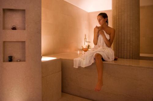 Una donna con un vestito bianco seduta su una vasca da bagno di Villasanpaolo Resort & Spa a San Gimignano