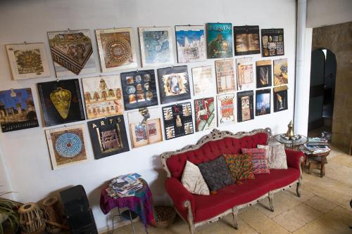 a living room with a red couch and a wall of posters at Mikes Khan in Abū Ghaush