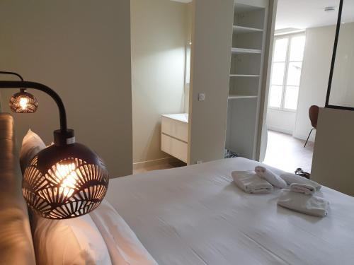 a bedroom with a bed with a lamp and two towels at Au Loup Historic Apartments in Bayeux