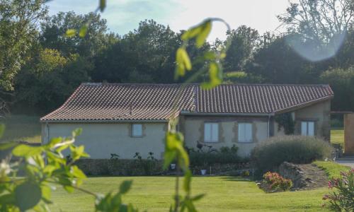 a white house with a red roof in a yard at La Villa a Bel-Endroit in Marciac