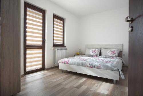 biała sypialnia z łóżkiem i 2 oknami w obiekcie Вили Алекс w mieście Elena
