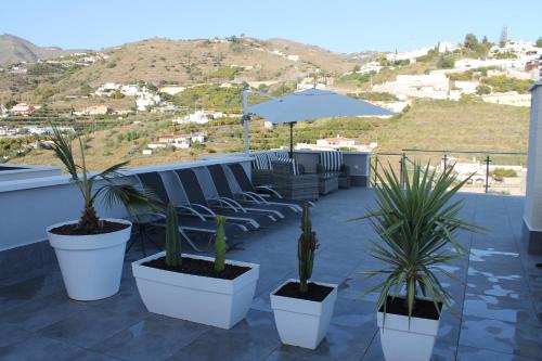 a patio with potted plants and an umbrella at Dúplex playa Cabria in Almuñécar
