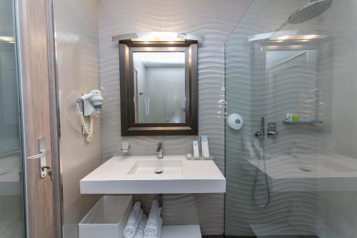 a white bathroom with a sink and a shower at Demi Hotel in Sarandë