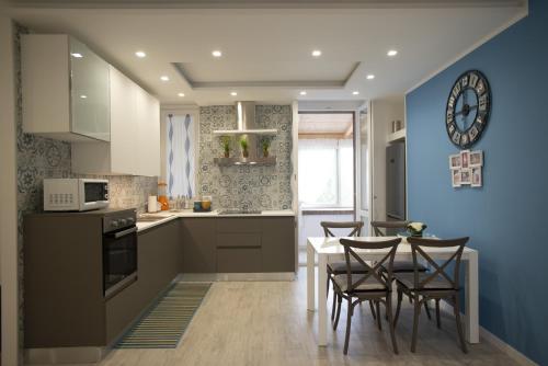 uma cozinha com uma mesa e cadeiras e uma parede azul em Appartamento Roberto House em Fertilia