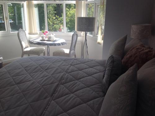 um quarto com uma cama, uma mesa e janelas em Oakleigh house em Stratford-upon-Avon