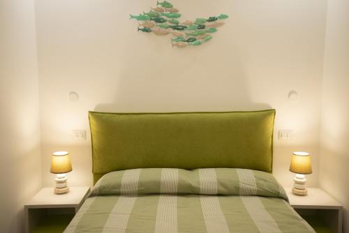 a bedroom with a green bed with two lamps at Appartamento Roberto House in Fertilia