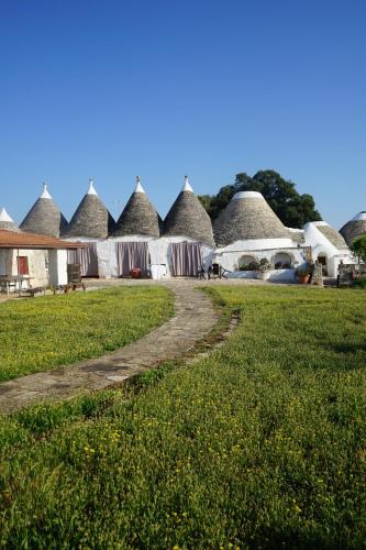 a row of thatched huts with a dirt road at Masseria Ferri in Ostuni