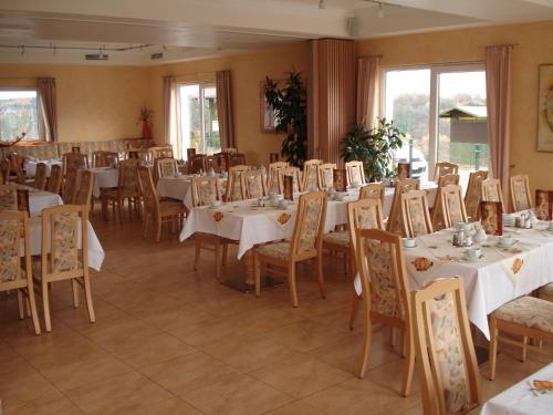 una sala da pranzo con tavoli e sedie bianchi di Panorama Hotel am Frankenstein a Witzelroda