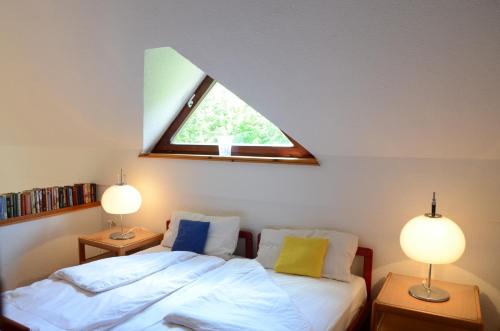 1 dormitorio con 1 cama con 2 lámparas y una ventana en Architect’s house - peaceful and minimalistic, en Bled