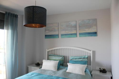 1 dormitorio con 1 cama con almohadas azules y blancas en Suite Home Los Alamos sol, playa y golf , parking&Wifi, en Torremolinos