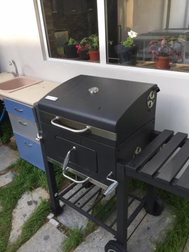 a black barbecue grill sitting next to a window at Family Hotel Malibu in Chernomorets