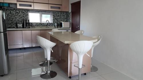 a kitchen with white chairs and a island in a kitchen at Easy World Beach Apartments in Flic-en-Flac