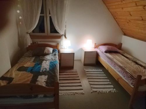 two beds in a room with two lamps and a window at Mandarynkowy in Dębki