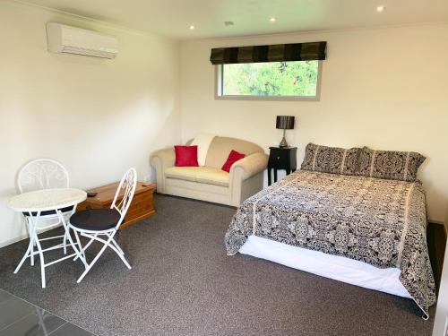 1 dormitorio con 1 cama, 1 mesa y 1 silla en Mirror Creek Holiday Cottage en Ruatapu