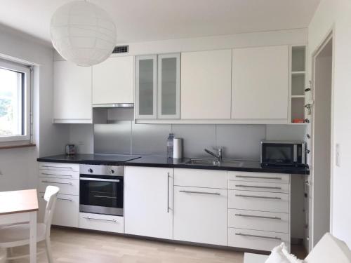 a kitchen with white cabinets and a black counter top at GreenPlace City Apartment in Bern