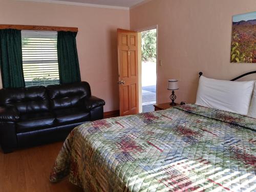 a bedroom with a bed and a black leather couch at Riverbend Lodging in Bryson City
