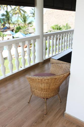 a porch with a wicker chair and a white railing at Villa Dahl Beach Resort in Dar es Salaam