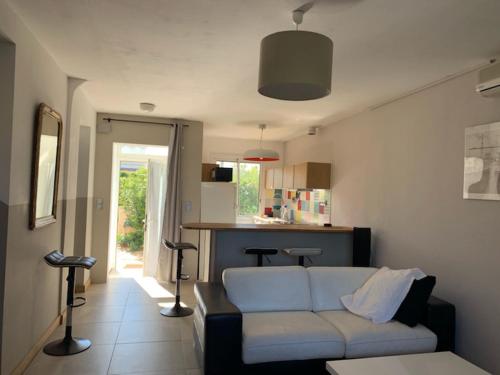 Una sala de estar con un sofá y una cocina. en Maison Bord de Mer, en Six-Fours-les-Plages