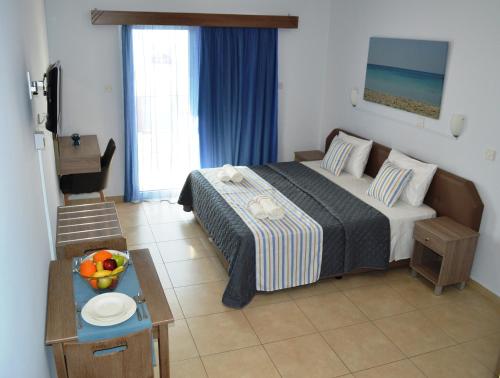 a bedroom with a bed and a table with a bowl of fruit at Millie's Apartments in Ayia Napa