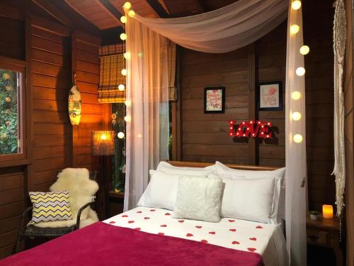 1 dormitorio con 1 cama blanca con dosel en Cabana Encantos da Lagoa, en Imbituba