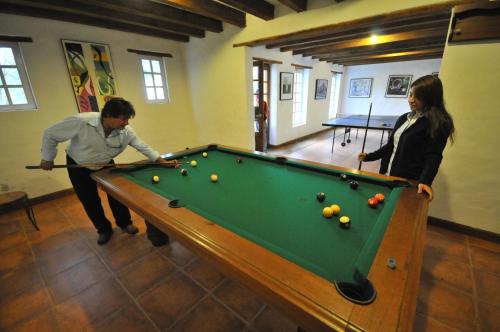 een man en een vrouw die een spelletje pool spelen bij Las Palmeras Inn in Otavalo