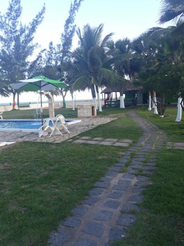 a walkway next to a swimming pool with palm trees at Pousada Cataventos in Sirinhaém