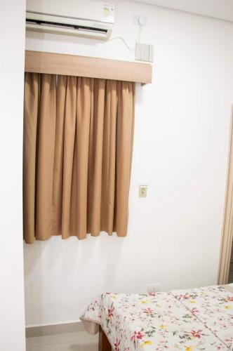 a bedroom with a bed and a curtain at Hotel Morada do Mar in Guarujá