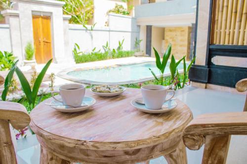 una mesa de madera con dos tazas de café. en Alam Grigis Ubud, en Ubud