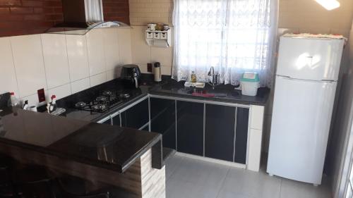 Una cocina con un refrigerador blanco y un fregadero. en Rancho Paraíso, en Capitólio