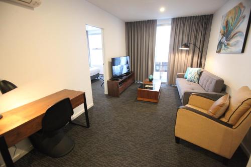 a living room with a couch and a tv in a room at The Palms Apartments in Adelaide