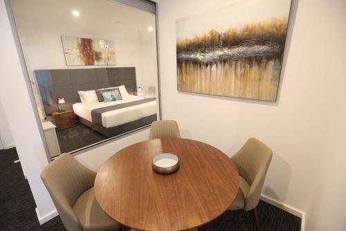 a dining room with a table and a bed at The Palms Apartments in Adelaide