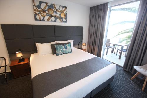 a bedroom with a large bed and a large window at The Palms Apartments in Adelaide