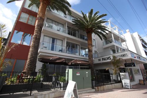 um edifício com palmeiras em frente em The Palms Apartments em Adelaide