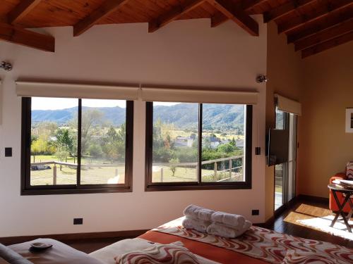 Un dormitorio con una gran ventana con montañas en el fondo en Suites del Sol en Villa General Belgrano