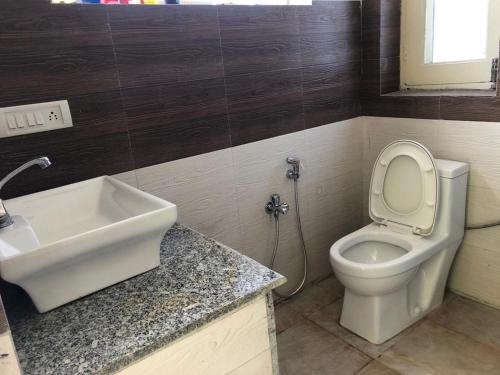 a bathroom with a white toilet and a sink at Blue Mountain Village Cottage in Nainital