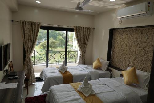 una camera d'albergo con due letti e una finestra di Rama Golden Root New town a Calcutta