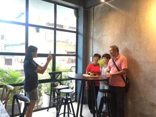 a group of people standing around a table in a restaurant at Goodnight Poshtel + Free Netflix in Hat Yai