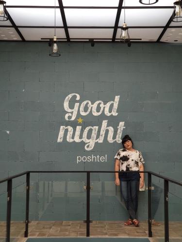 a woman standing in front of a wall with a good night sign at Goodnight Poshtel + Free Netflix in Hat Yai