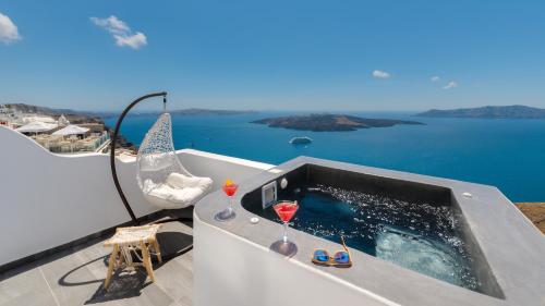 a bath tub with two glasses of wine on a balcony at Katris Apartments in Fira
