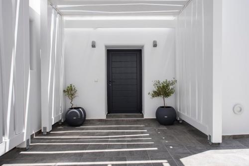 a hallway with a black door and two potted plants at Aurum in Kamari