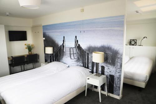 a bedroom with two beds and a painting of a beach at Heeren van Noortwyck in Noordwijk aan Zee