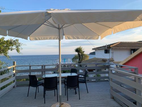 a patio with a table and chairs under an umbrella at Hamre Apartments (Nicholas) in Agios Georgios Pagon
