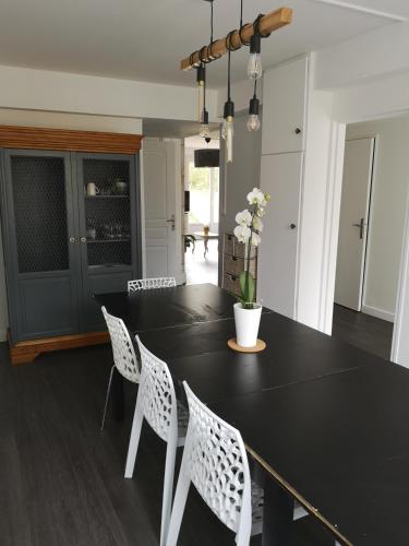une salle à manger avec une table noire et des chaises blanches dans l'établissement Les bulles champenoises, à Châtillon-sur-Marne
