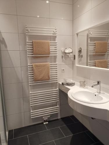 a white bathroom with a sink and a mirror at Hotel-Hofbräu am Stadtring in Nordhorn