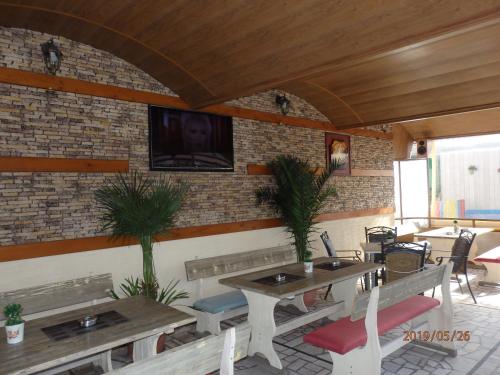 a restaurant with tables and chairs and a tv on a brick wall at Guest house Napoli in Ravda