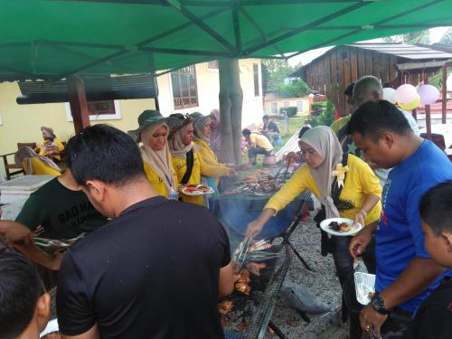 a group of people standing around a grill with food at Challet Chengal in Kota Bharu